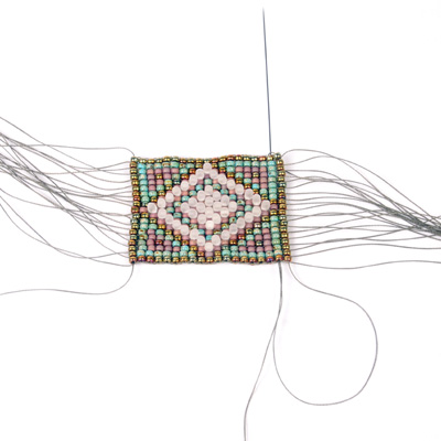 Weaving weft threads on loom bracelet
